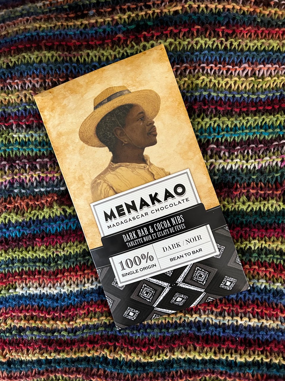 A bar of Menakao 100% cocoa chocolate is on a brightly coloured knitted blanket. Image by Rowan Ambrose.