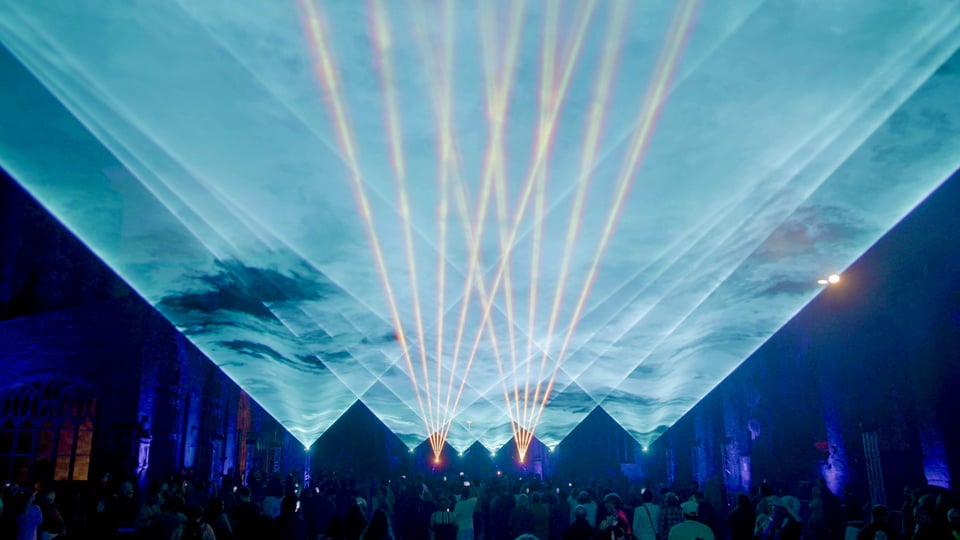 An image of the laser show Polaris, with cyan and orange laser beam effects