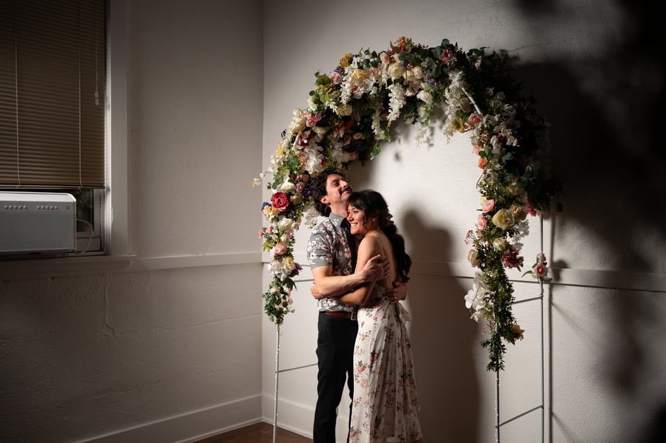 Ivan and Livvy hugging under the flower arch.