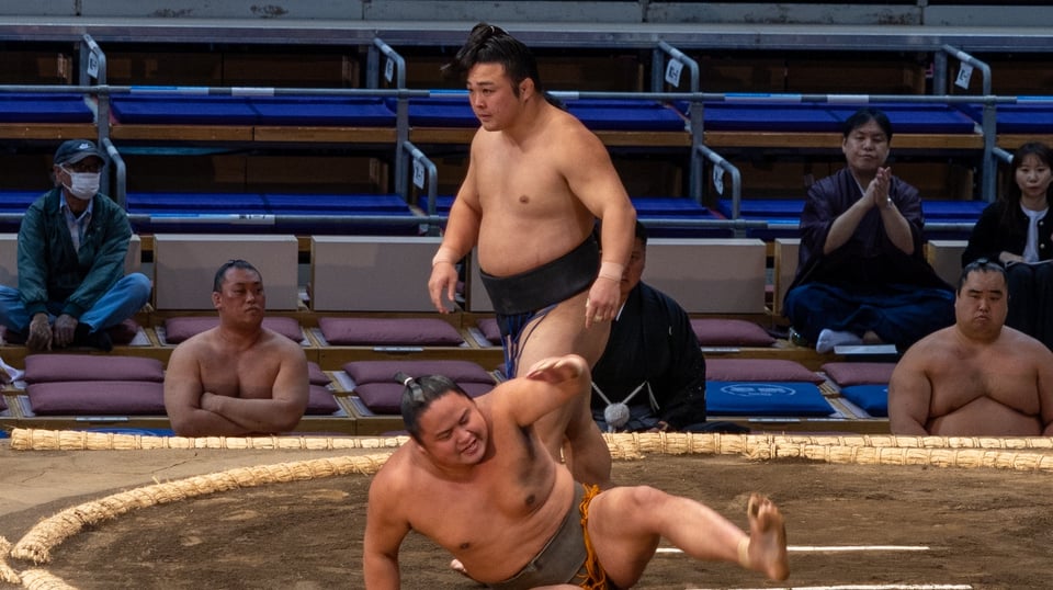 Sumo wrestler Enho stands victorious above his opponent.