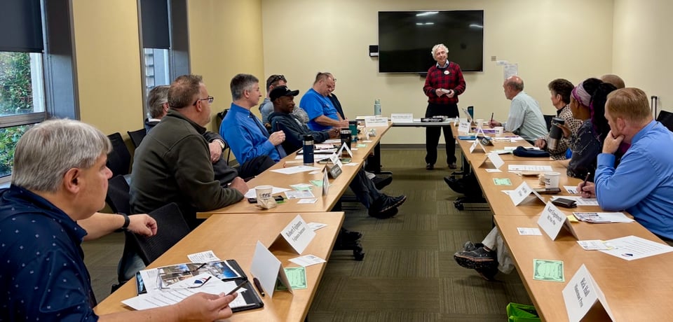 Kurt stands at the front of a room presenting to seated NRG members.