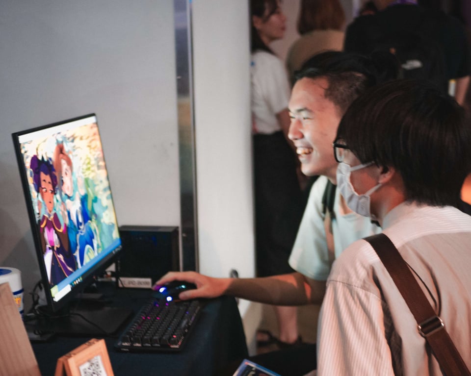 Two people smiling and laughing as they're playing a game on a Windows PC console. They look like they're having fun.