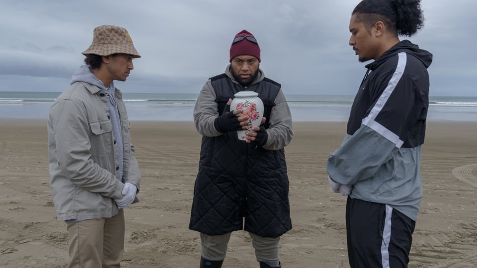 Three men on beach with urn