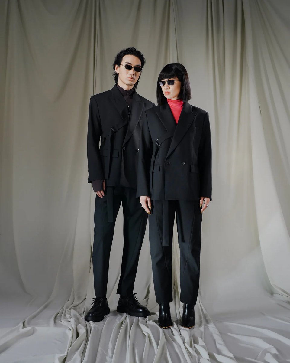A man and a woman, both wearing the Harness Suit by Rosen.