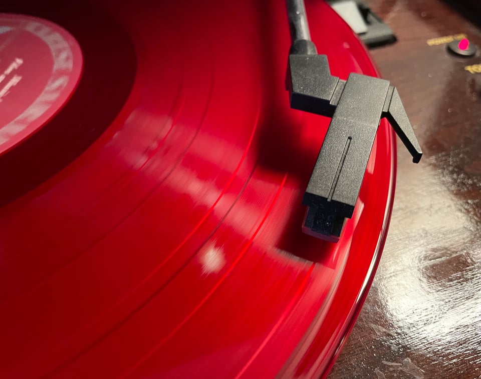 A close-up photo of a record player stylus on a red, spinning record