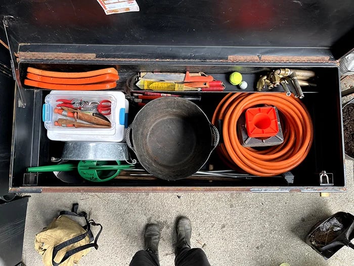 Inside the tool box of a gardner: clippers, watering can, bucket, a hose, etc.