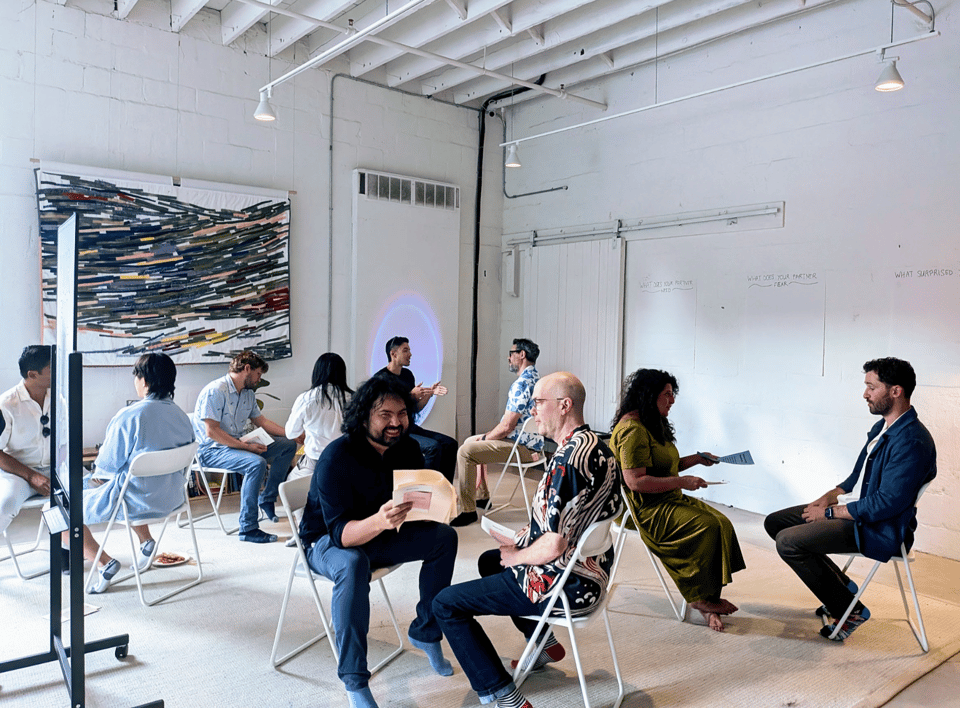 FIve pairs of people sit facing each other, engaged in 1:1 conversation.