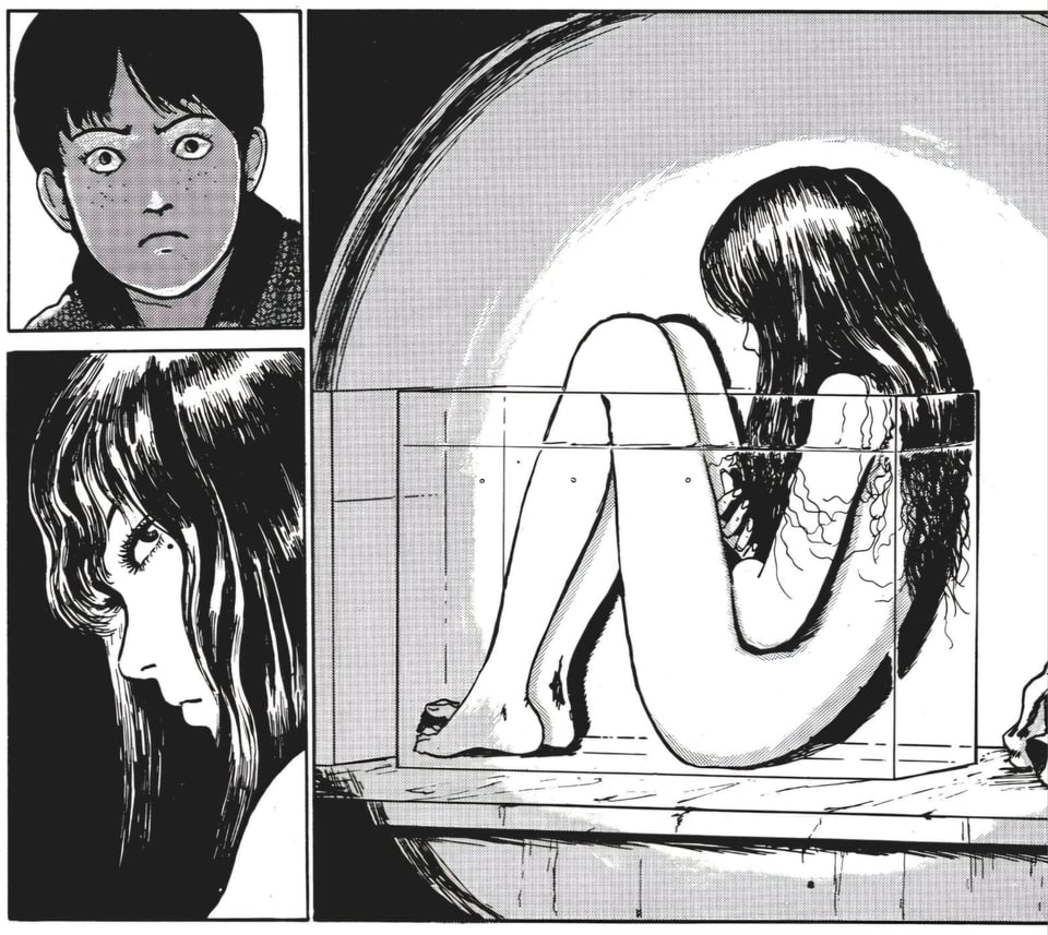A young man finding a sad-looking Tomie nude in an observation tank in a dark room