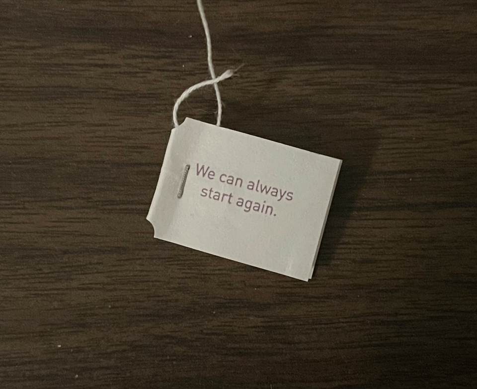 A close-up of the paper tab on a tea bag that reads "We can always start again"