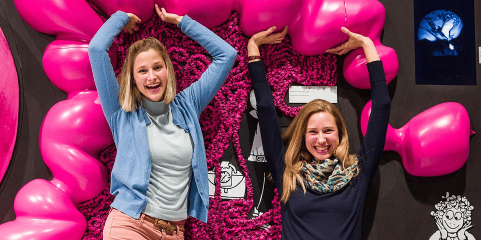 Two women jumping around the inside of a model gut.