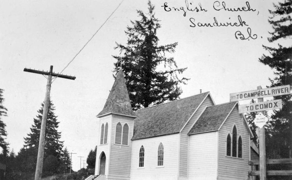 Black and white photo of a small wooden church with steeple. A wooden sign at the bottom left of the photo reads "To Campbell River - To Comox." Handwritten in cursive at the top of the photo it reads "English Church, Sandwick, BC"