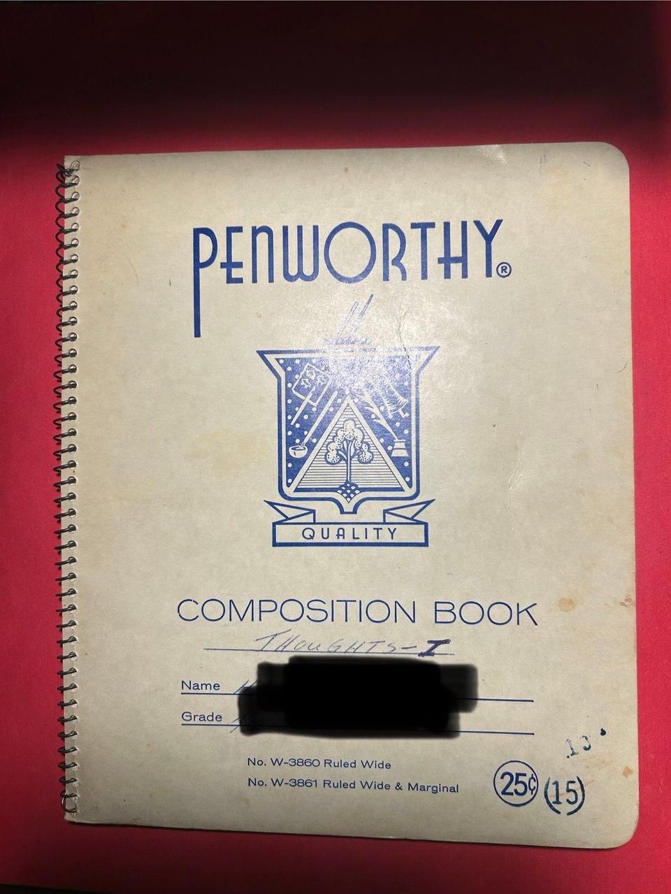 The white and blue cover of a spiral bound Penworthy composition notebook, with the words THOUGHTS - I handwritten on the title line