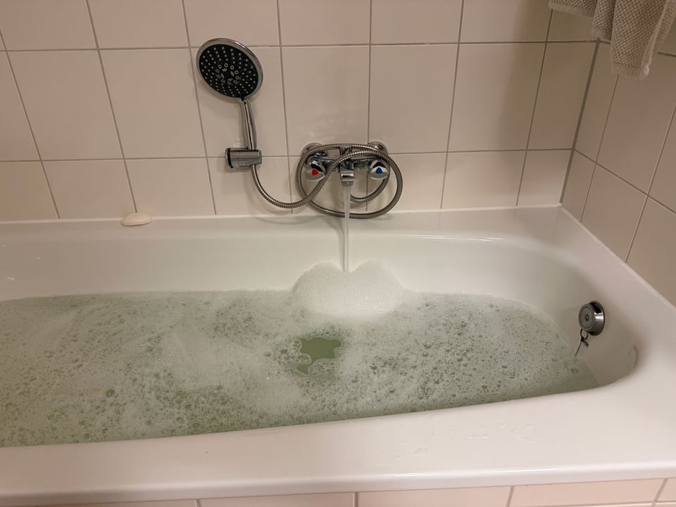 A bathtub is filling up with water and bubbles.