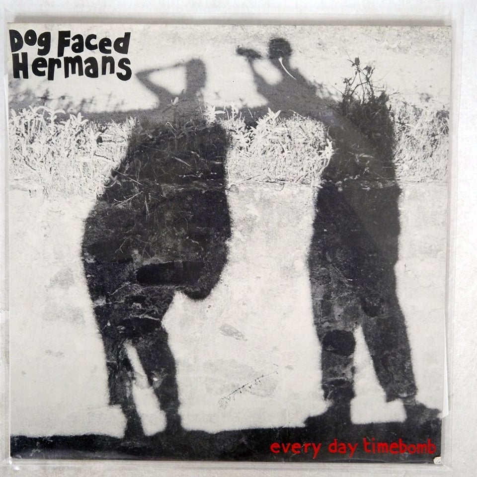 A black and white photo of the ground, with two shadows across the ground. Shadow on the left appears to be a woman, carrying a bag and holding a hand to her brow, possibly to block out the light. On the right is a shadow of a man, who I believe is holding out the camera that is taking the picture. It looks like his head is missing?