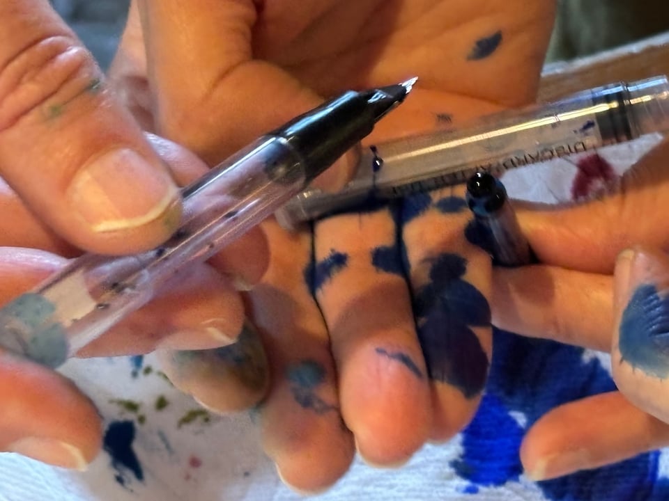 Several hands stained with fountain pen ink