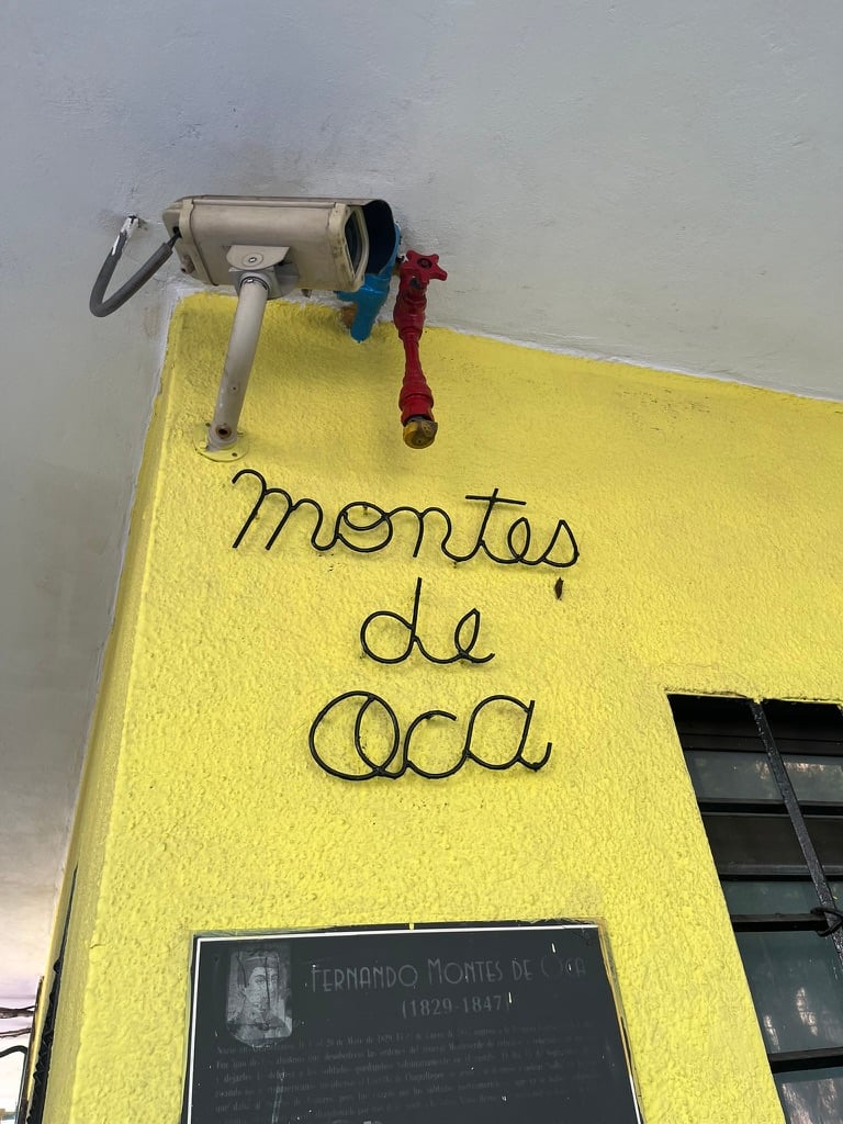 Bent metal script letters on a yellow wall