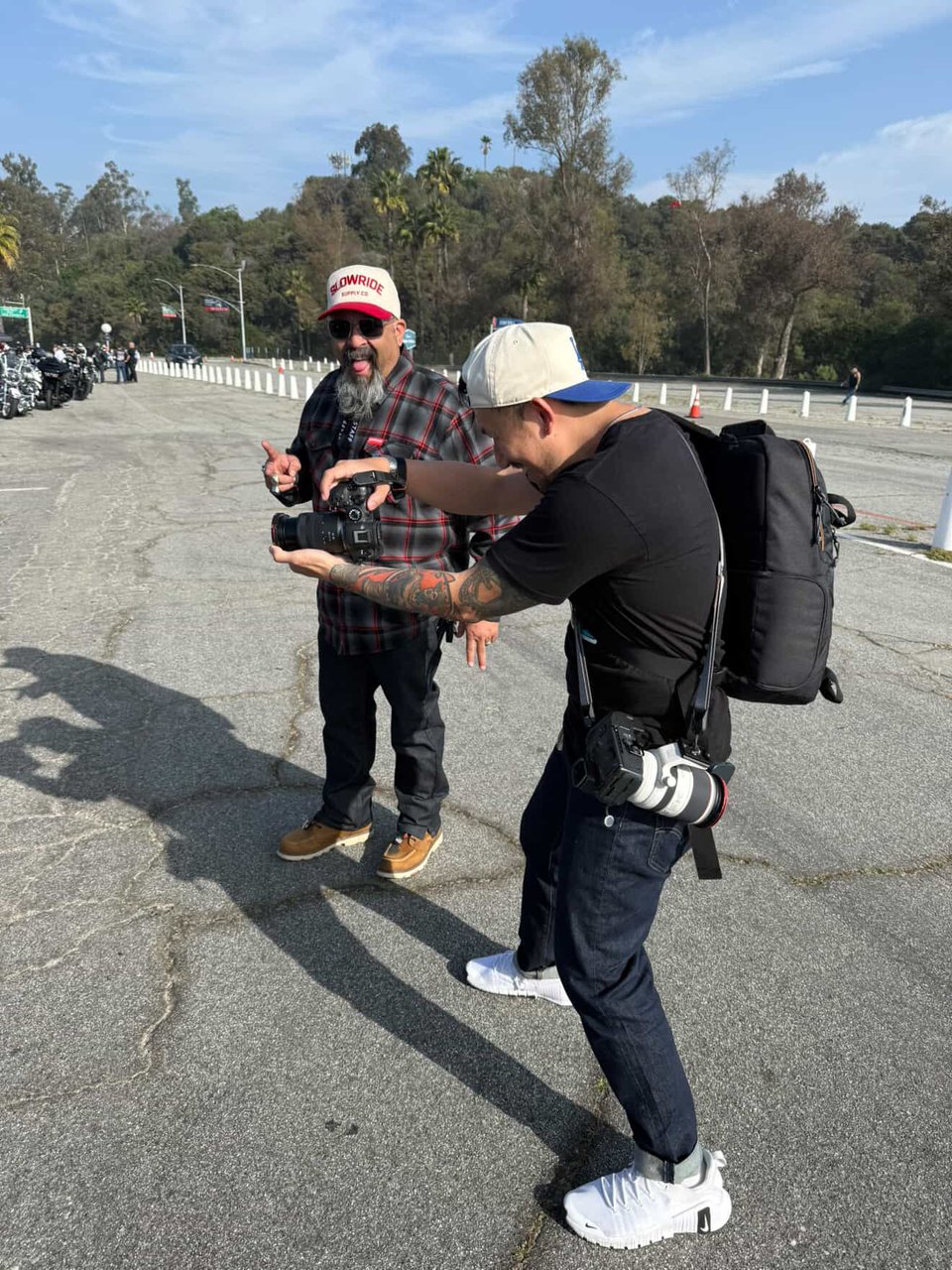 A photo of me holding at an event raising one of my cameras in my hands to photograph, with my second camera hanging from a shoulder strap at my hip.