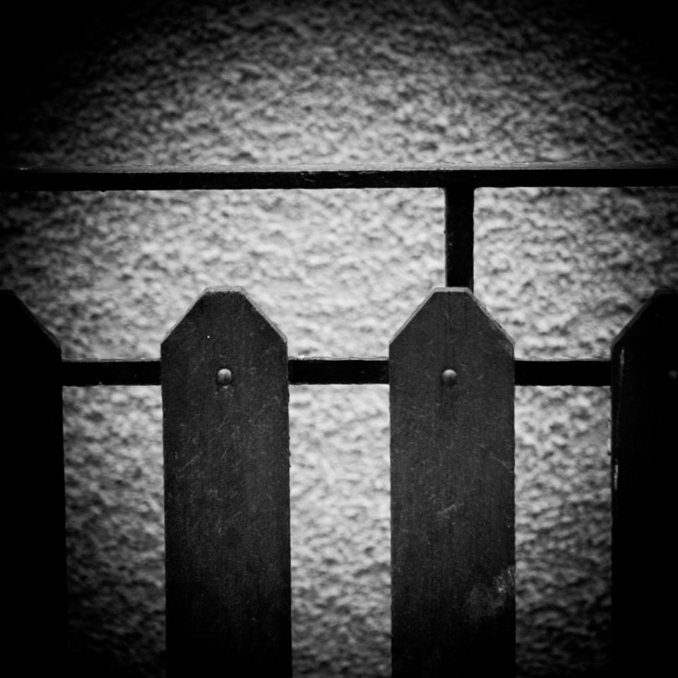 Regular - and irregular fence, behind it a coarse stone wall.