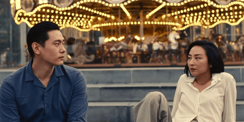 A man and woman sitting next to a carousel.