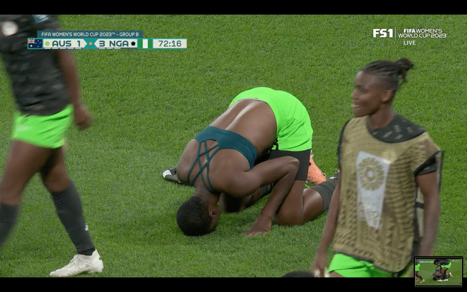 Asisat Oshoala, in green shorts and a sports bra performing sajdah after scoring for Nigeria. The score bug shows the score as Australia 1 to Nigeria 3 in the 72nd minute