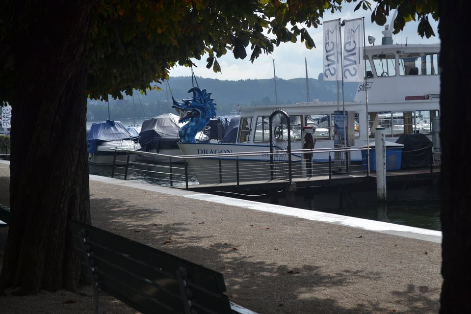 A white boat with a blue dragon figurehead berthed in a harbor.