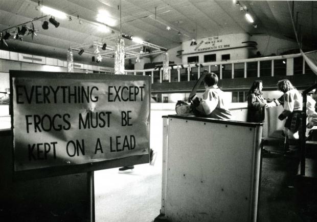 An interior photo of the ice-ring with the huge single span roof and balconies for spectators. In the foreground is a sign reading 'everything except frogs must be kept on a lead'.