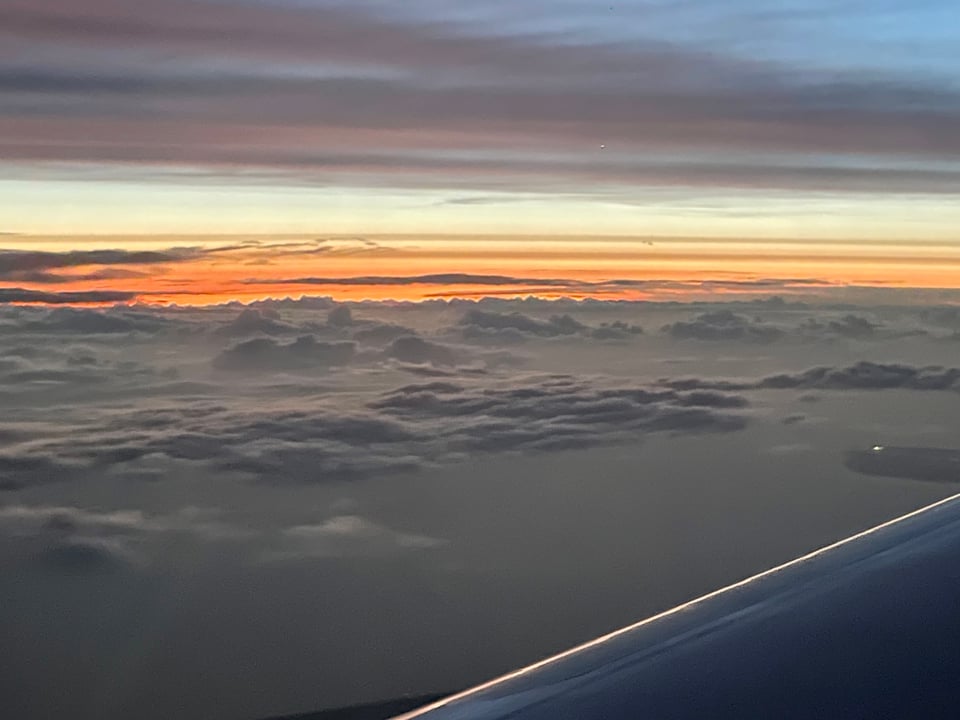 Sunset over the clouds as seen from a plane window.