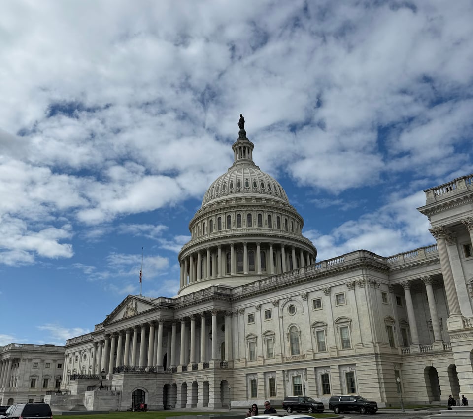 Photo of US Capitol building with clouds and a blue sky behind it
