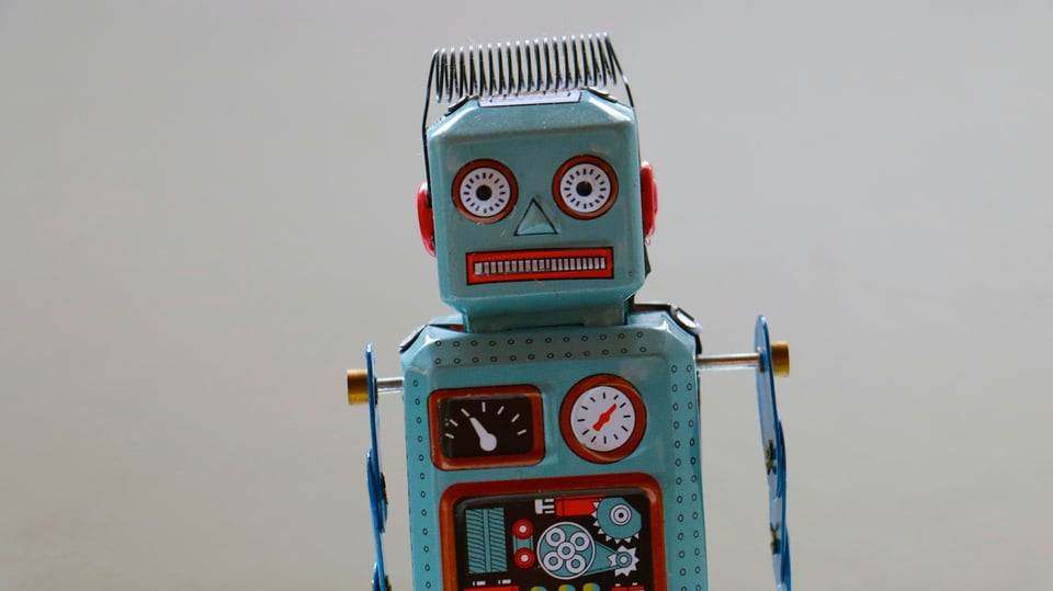 A blue toy robot with various dials and gauges whose mouth and eyes look like it's being electrocuted.