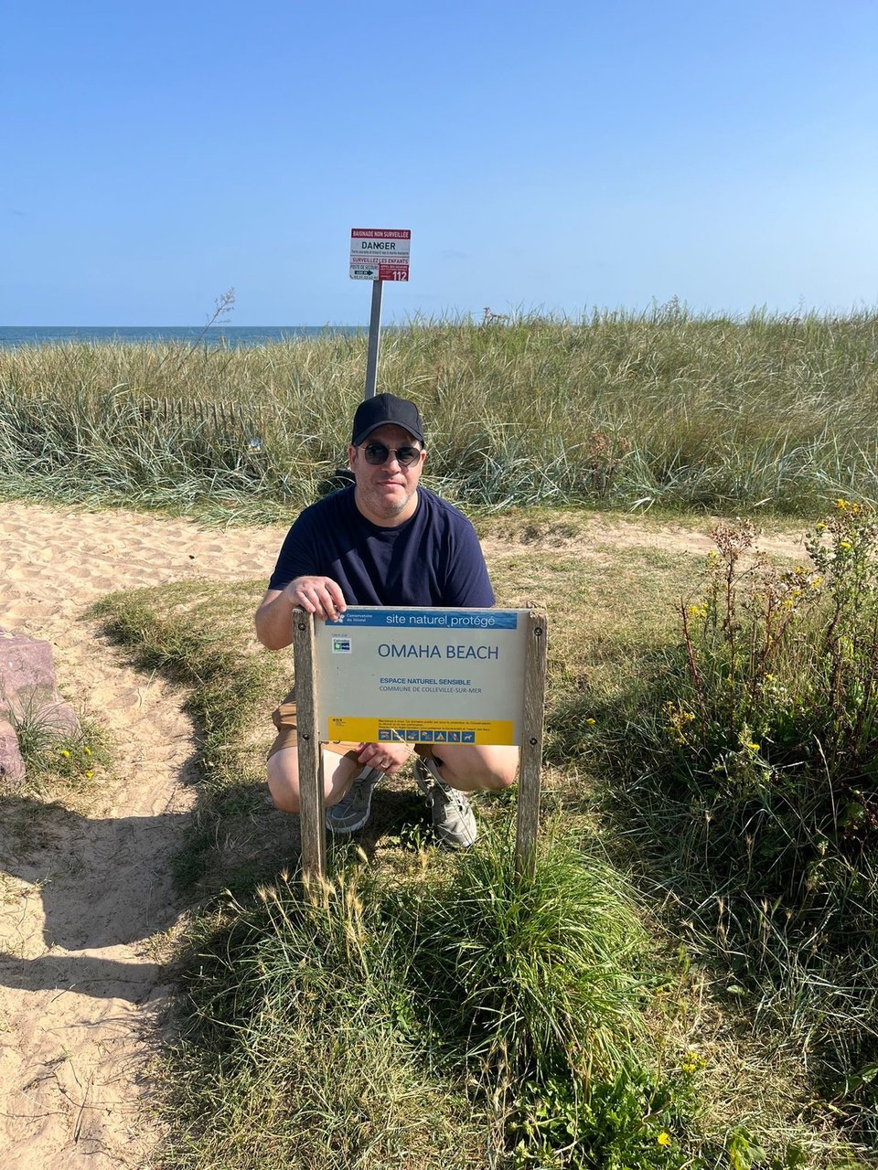 neil on omaha beach, normandy, by the omaha beach sign