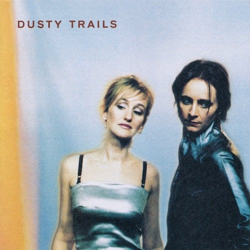 This is the cover of Dusty Trails’ self titled album, which has members Vivian Trimble, in a silver dress, Josephine Wiggs in I think a black leather jacket, standing against a grey-blue scrim, with a strip of orange on the left.