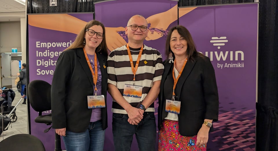 Three people stand in front of a tradeshow booth for Niiwin by Animikii at the Indigenous History and Heritage Gathering