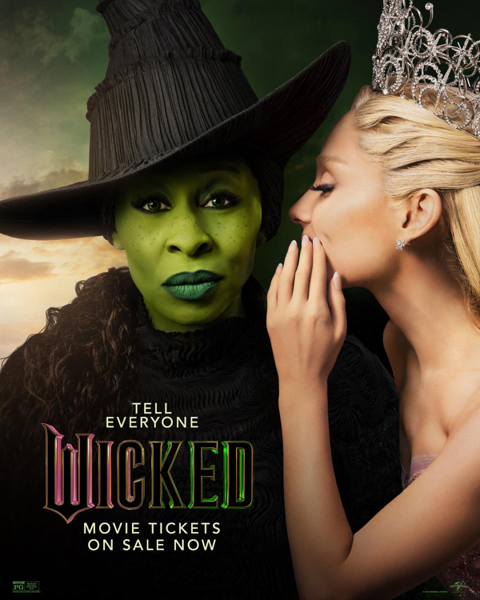 The promo poster for the movie Wicked. A promotional poster for the film "Wicked" featuring a close-up of the two main characters. On the left is Elphaba (the Wicked Witch) with green skin, wearing a black pointed witch hat and dark clothing, looking directly at the camera. On the right is Glinda, with blonde hair and a silver tiara, whispering into Elphaba's ear. The background has a dark green tone with hints of a sunset sky. Text at the bottom reads "TELL EVERYONE" above the "WICKED" logo, and "MOVIE TICKETS ON SALE NOW" underneath.
