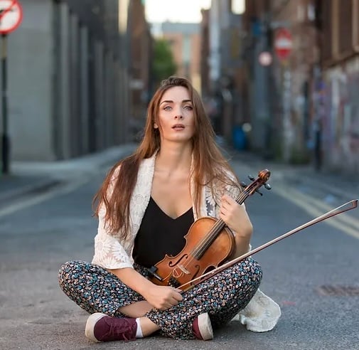A seated performer holding her violin