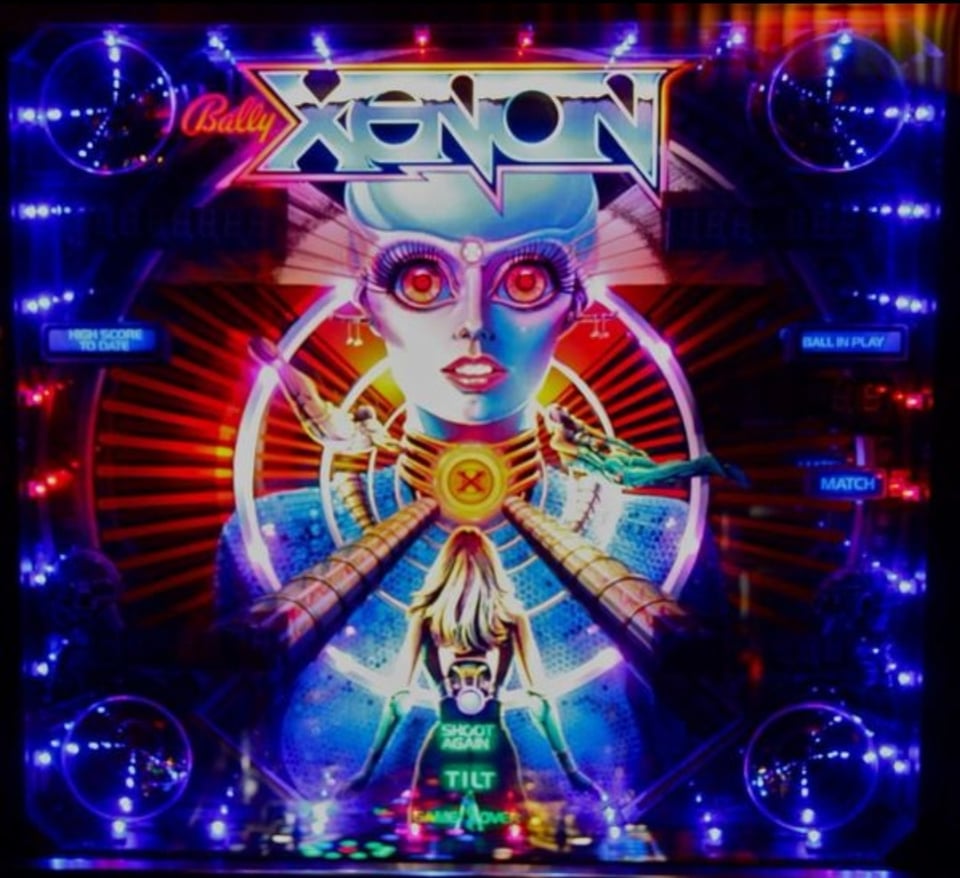 Photo of backglass of a Bally XENON pinball machine, showing a robot woman with lipstick and receding lights framing her
