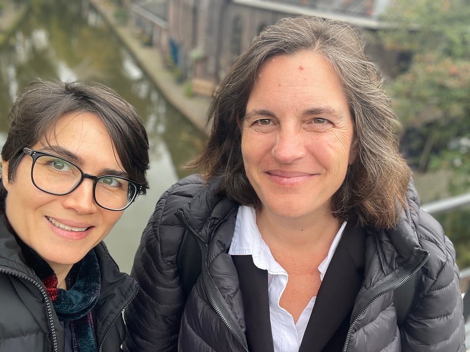 Two women look at the camera as they stand next to a canal in downtown Utrecht.