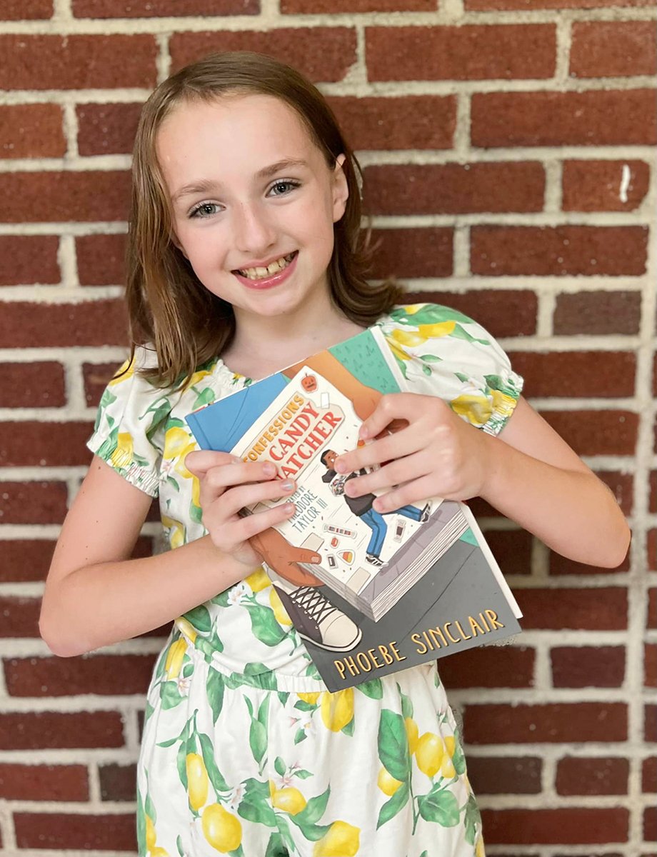 young girl in lemon-print dress holds a book