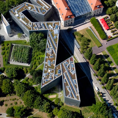 A satellite view of a building that sharply zig-zags through a tree-filled park area.