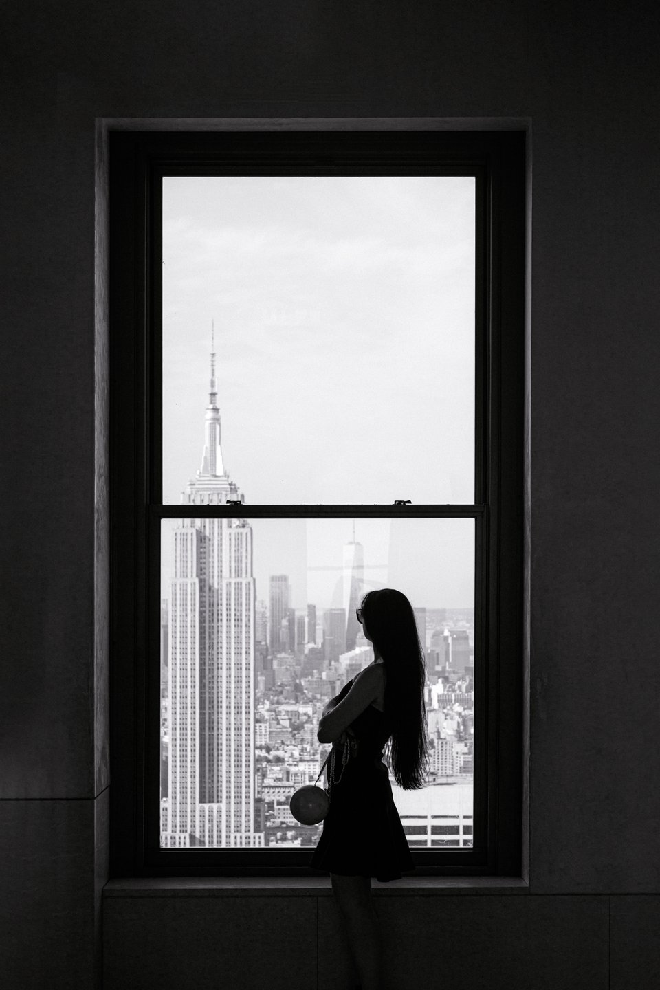 black and white photo, Anna is silhouetted in a window with the empire state building behind her