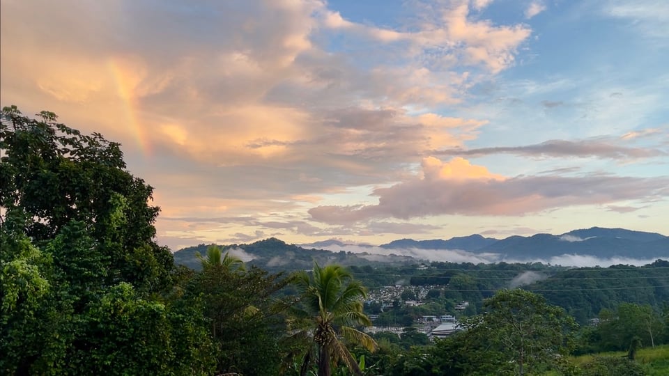 Photo of a mountain landscape with clouds and a rainbow