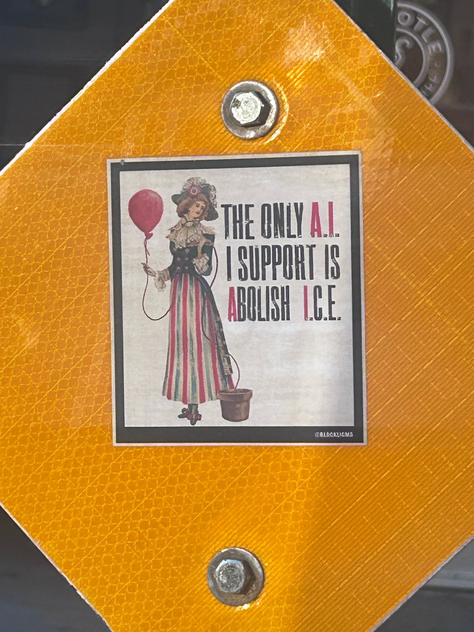 On a yield sign, someone has put a sticker with a fancy lady holding a balloon that reads "The only AI I support is Abolish ICE"