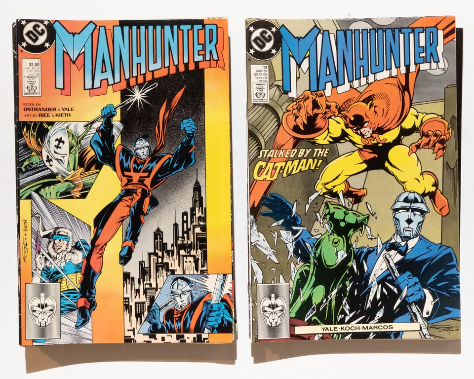 two stacks of Manhunter comics side by side. issue 1 is on top of the left pile, while issue 13 is on top of the right pile.