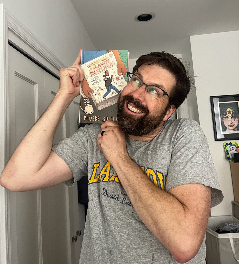 man holds a book on his shoulder