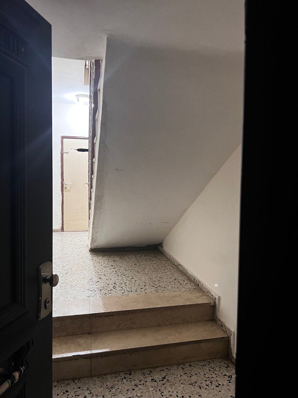 Space under a stairway in a small building, with a tile floor