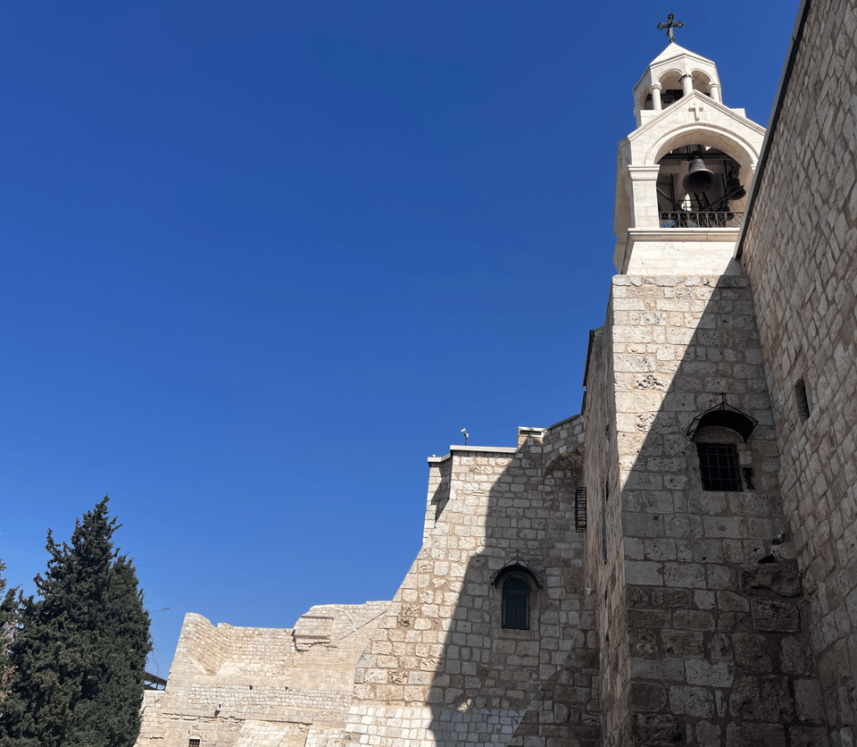 A stone wall and a steeple against a bright blue sky