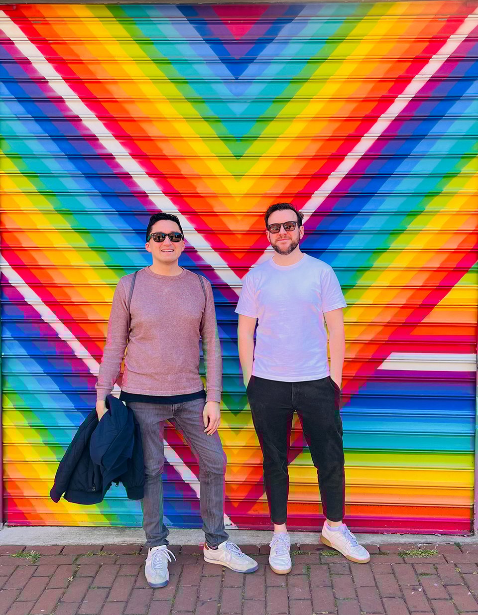 The author and his friend standing in front of a colorful mural.