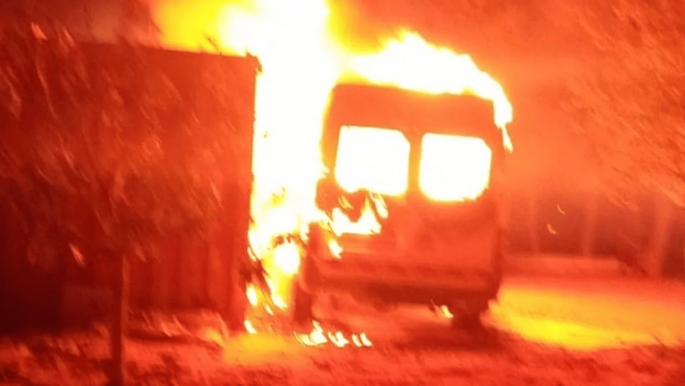 A small bus on fire at night