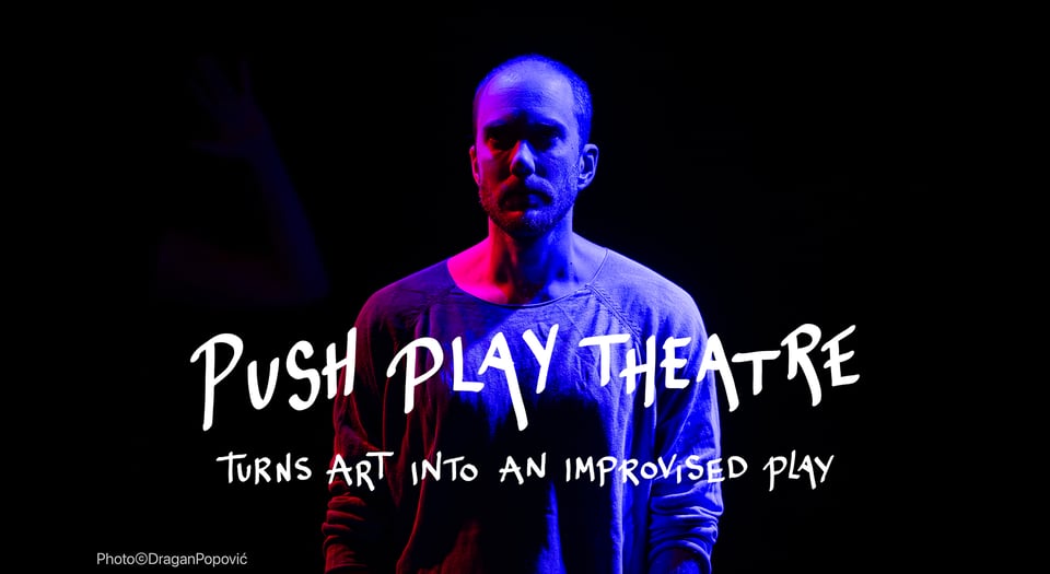 A photo from a previous show. A guy with a black background and very dim, gloomy lighting lighting his face and upper body with dark pink, purple and blue. The text says "Push Play Theatre turns art into an improvised play".