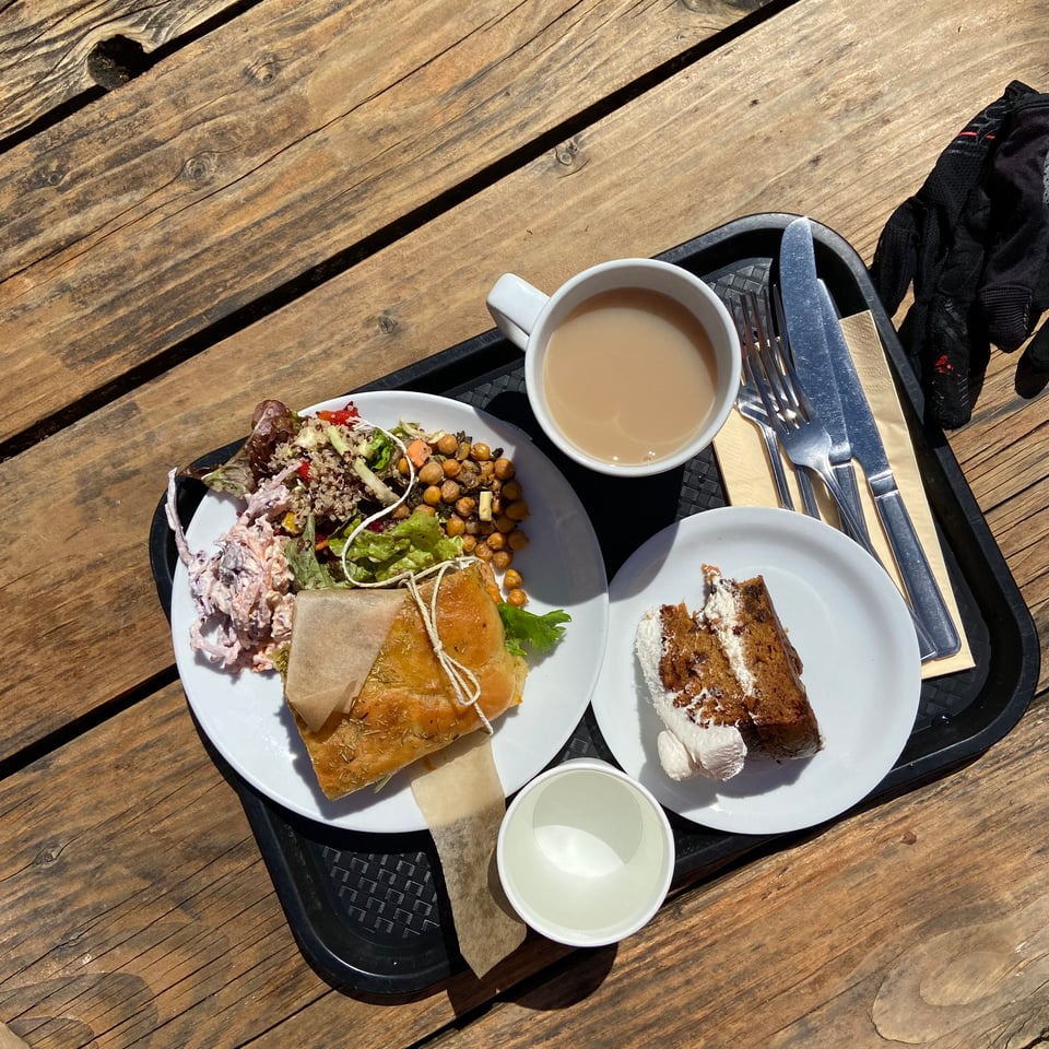 a tray with tea, a focaccia and a large slice of carrot cake with frankly too much icing