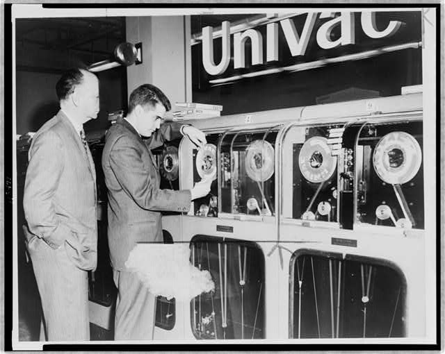 [One man looks on as another man prepares Univac computer to predict a winning horse.]
